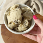 A hand holding a bowl of healthy banana chocolate chip ice cream